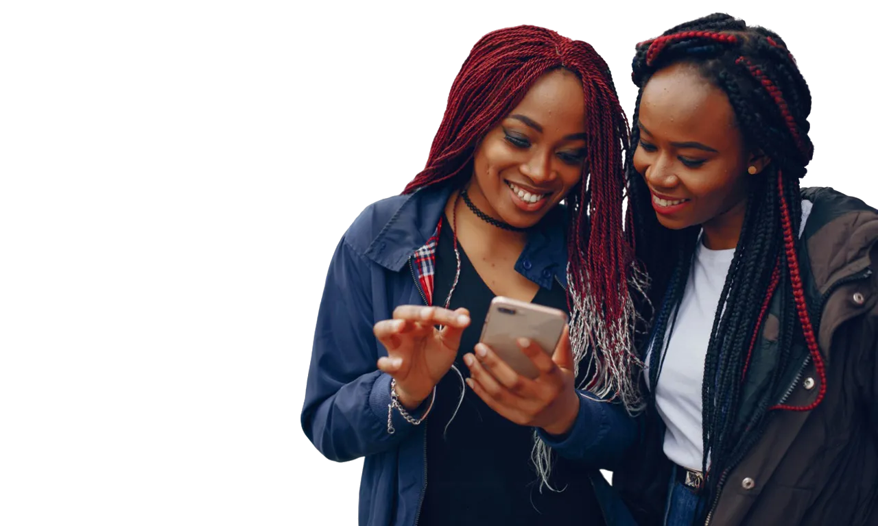 Two young Kenyan women smiling while looking at a phone together