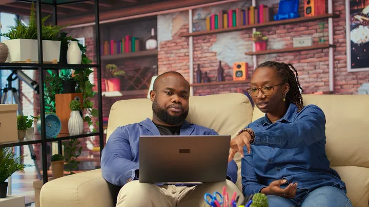 Two parents at home looking at a laptop together